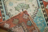 Antique Turkish Oushak rug folded, revealing rich pile, cream field, turquoise, and terracotta patterns.