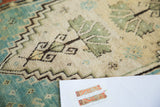 Plush pile of an Antique Turkish Oushak rug, featuring green leaf motifs and a jagged teal border.