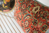 Textured surface of antique Herati Bijar pillow with red, blue, green, and ivory floral motifs.