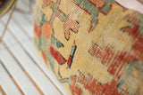 Aged yellow Serapi rug fragment pillow showing woven texture with muted red and teal patterns.