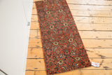 Long, narrow antique Bijar fragment mat with intricate bold red pattern.