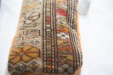 Floral vintage Caucasian rug fragment pillow with unique woven patterns and tangerine velvet trim.
