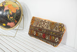 Oblong vintage Caucasian rug fragment pillow displaying geometric floral motifs and tangerine velvet edge.