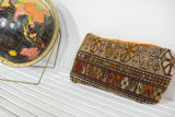 Vintage Floral Caucasian rug fragment pillow, with geometric patterns in earthy tones and orange velvet.