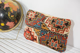 Antique Kazak rug fragment pillow with bold geometric pattern, gold velvet trim.