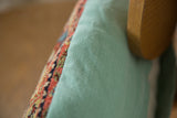 Intricate antique Bijar rug border fragment against the faded turquoise linen back.