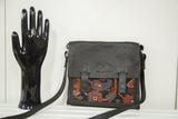Rug fragment messenger bag with geometric dark blue and red antique Kazak pattern.
