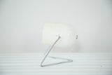 White Mid Century spotlight desk lamp with triangular chrome base showing slight paint chipping.