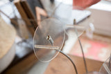 Oval lucite top plate and chrome hardware of vintage hat stand, showing surface wear.