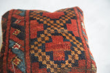 Antique Afghani rug fragment pillow with rich red, blue, and gold geometric diamond motifs.