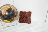 Antique Afghani rug fragment pillow featuring red, blue, and gold geometric diamond design.