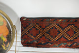 Textured antique Afghani pillow with rustic red, blue, and golden diamond motif.