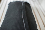 Black European linen pillow back, showing subtle texture and white zigzag stitch.