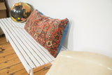 Detailed side view of the antique Bijar lumbar pillow with blue fabric and patterned fragment.