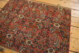 Intricate floral and vine pattern on an antique Bijar rug, displaying bold red, blue, and cream motifs.