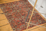 Intricate beige and blue floral patterns on the bold red antique Bijar rug.