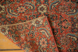 Close-up of the intricate hand-knotted red, blue, and beige patterns on an antique Bijar rug.