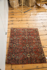Secured corner of the antique Bijar rug fragment, showcasing fine weave and bold red intricate motifs.