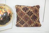 Antique Turkmen rug fragment pillow corner, featuring geometric deep brown, rust, and khaki motifs.