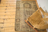 Earthy brown geometric border and distressed texture on a vintage Caucasian rug.