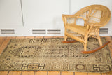 Distressed vintage Caucasian rug with earthy geometric patterns and natural brown pile texture.