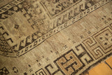 Distressed vintage Caucasian rug with earthy geometric patterns and faded natural browns.