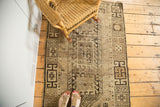 Geometric patterns and earthy distressed tones along the secured edge of the vintage Caucasian rug.