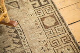 Distressed geometric border of a vintage Caucasian rug in natural camel tones.