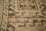 Distressed texture of a vintage Caucasian rug, showing geometric motifs and faint pink threads.