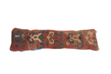Antique Kazak fragment pillow displaying geometric motifs in madder red, indigo, and cream.
