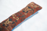 Antique Caucasian Kazak rug fragment pillow; terracotta, teal, and beige geometric pattern, cobalt blue back.