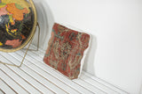 Angled view of unique antique Heriz rug pillow, rich red and beige geometric pattern.