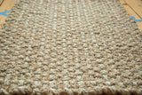 Durable hand-braided texture of the entrance mat, featuring natural beige and tan fibers.