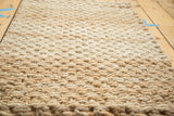 Thick hand-braided texture of a beige natural fiber entrance mat.
