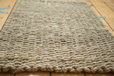 Surface texture of a durable, hand-braided natural fiber grey entrance mat.