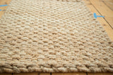 Close-up of the ivory hand braided entrance mat's dense natural fiber texture.