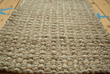 Hand braided natural fiber entrance mat with textured beige and tan weave.
