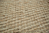 Detailed view of the tightly hand-braided texture of a gold natural fiber mat.