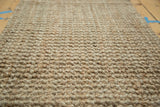 Dense, hand-braided texture of natural gold hemp and jute fibers on the entrance mat.