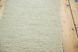 Close-up of the plush, hand-woven ivory shag pile of the Moroccan bath mat.