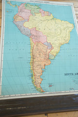 Angled view of the entire antique pull-down map of South America, showing its colorful countries and vintage paper.