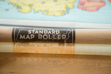 Wooden dowel of vintage pull-down map, showing 'STANDARD MAP ROLLER' label and map edge.