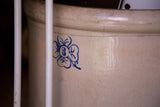 Detailed blue clover and '8' motif on a textured antique beige crock.