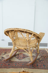 Vintage boho wicker child's rocking chair, side view highlighting open weave and wooden rockers.