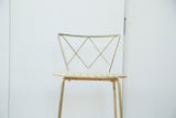 Patinaed brass legs and a textured light beige seat of the vintage stool.