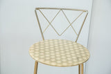 Upper portion of Hollywood Regency stool with brass geometric back and light hexagonal seat.