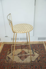 Hollywood Regency stool with hexagon-patterned seat and brass-tone frame.