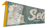Close-up of vintage felt pennant showing yellow stitched edge and grinning grey dolphin.