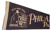 Dark felt Philadelphia pennant with light Betsy Ross House illustration and decorative lettering.