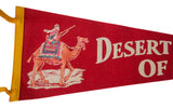 Vibrant red felt pennant shows camel rider with pink and blue saddle, 'Desert OF' text.
